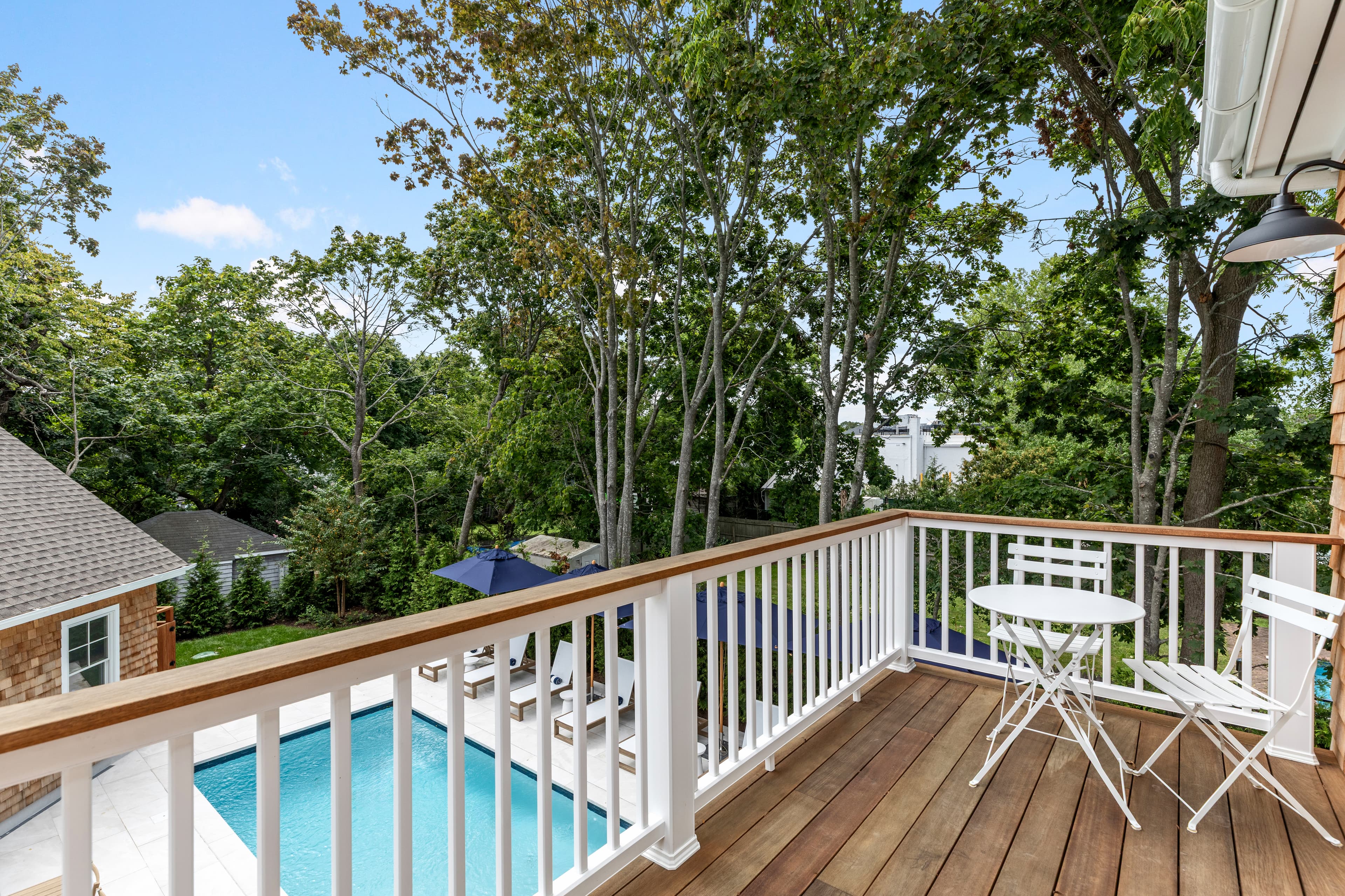 A balcony overlooking a pool surrounded by trees.